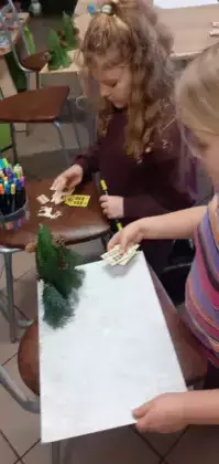 Dzieci z gałązek kleją choinki.