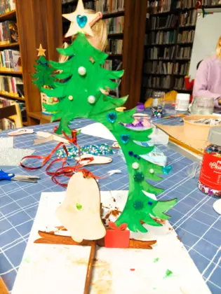 Pomalowana i ozdobiona drewinana choinka i dzwoneczek.