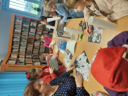 Uczestnicy zajęć zaczynają kolorować Mikołaje.