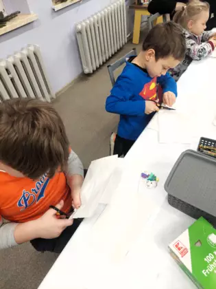 Dwóch chłopców szykuje torebki papierowe na gwiazdkę.