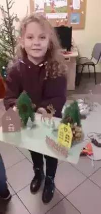 Dziewczynka trzyma w ręce makietę świąteczną.