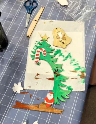 Pomalowana i ozdobiona drewinana choinka i dzwoneczek.